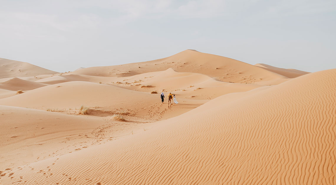 Sahara desert in Erg Chebbi Based in Morocco with two people walking in the landscape