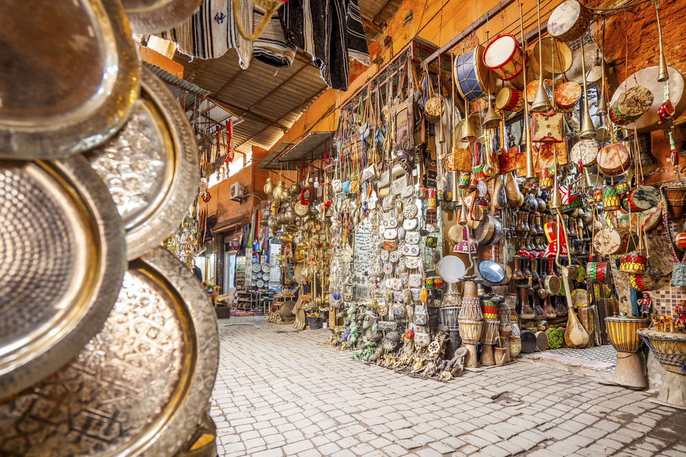 Narrow street in medina of Marrakech full of shops with metal and wooden art